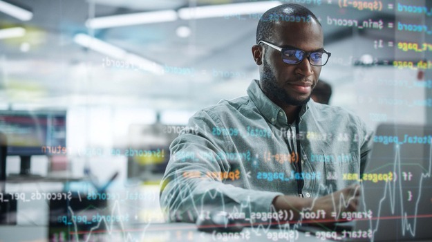 Modern Office: Portrait of Motivated Black IT Programmer Working on Laptop Computer. Male Specialist Create Website, Software Engineer Develop Programme. Shot with Visual Effects of Running Code.