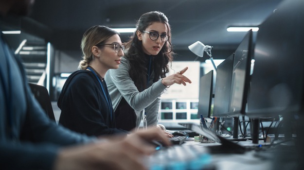 Two Women Working in a Cyber Security Software Development Department. Young Manager Updating Software Developer on the Artificial Intelligence Safety Project