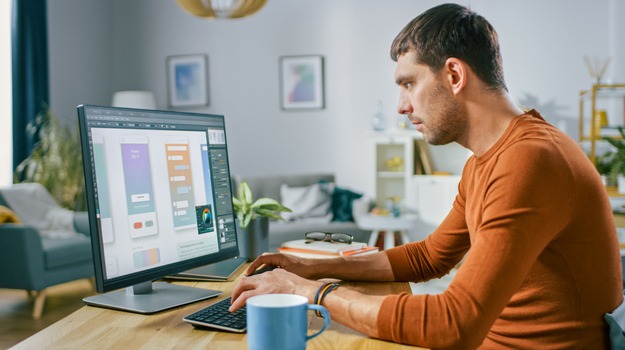 Software Engineer Works on a UX / UI Mobile App Template, Uses Personal Computer. Freelance Programmer Working At Home from Cozy Living Room.