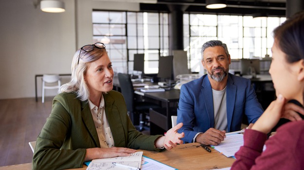 Smiling woman interviewing candidate for job selection in company. Happy recruiter taking and interview a candidate with the help of a human resources manager.